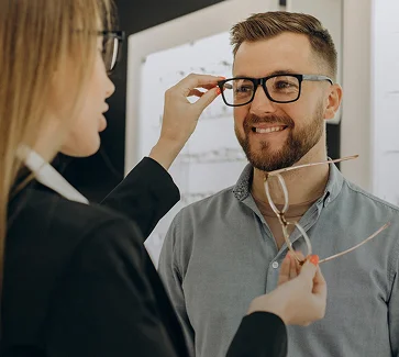 Optiker hjælper en kunde med brillernes pasform.